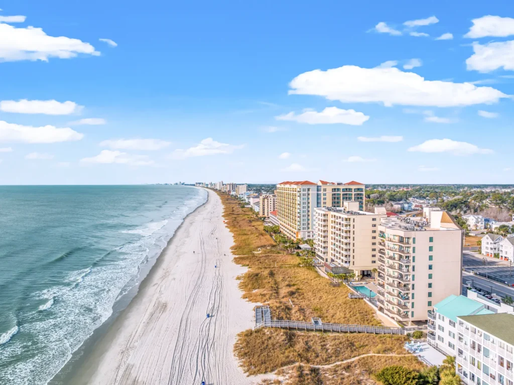 Aerial view of North Myrtle Beach, SC, featuring oceanfront condominiums, sandy beaches, and the Atlantic coastline on a clear sunny day.